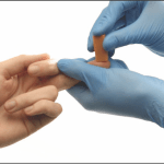 Image of gloved hands conducting a finger stick to analyze for biometric screening.